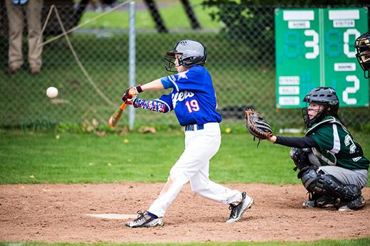 Juvenile baseball batter hitting the ball